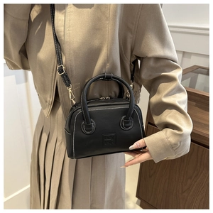 Close-up of black PU leather bag with white contrast stitching and gold hardware detail