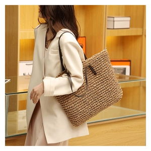 Detailed texture of hand-woven straw tote bag with brown leather shoulder straps