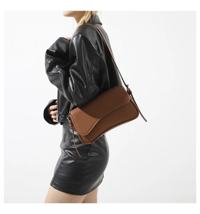 Close-up of brown litchi pattern leather shoulder bag on a model in a black jacket