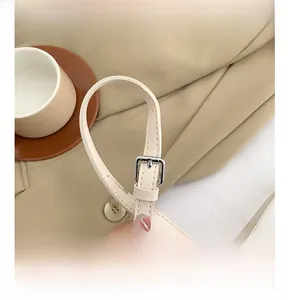 Gros plan sur la bandoulière réglable en cuir crème avec boucle en métal argenté