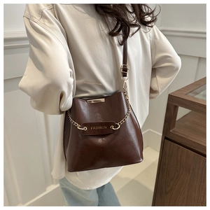 Détail du sac seau marron foncé en cuir PU avec chaîne dorée et étiquette Fashion