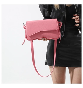 Detailed view of pink pebble grain leather handbag with stylish asymmetrical wave flap design
