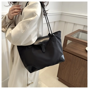 Vue latérale d'un grand sac cabas noir en nylon avec rabat et anses en cuir sur un modèle