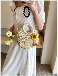 Detailed shot of beige straw crossbody bag with sunflower decor and pumpkin charms