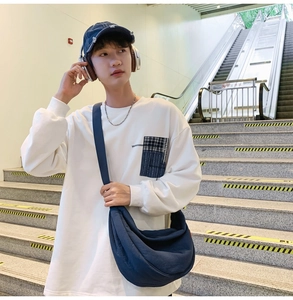 Detailed view of a large blue nylon crescent crossbody bag styled with casual urban outfit