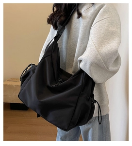 Detail of black canvas crossbody bag showing spacious capacity and side drawstring design