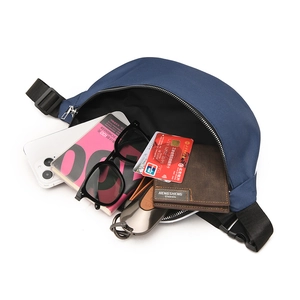 Detail view of spacious navy nylon sling bag interior with phone, wallet and accessories
