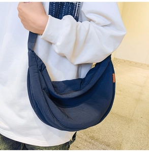 Detail view of navy nylon crescent bag showing adjustable strap and orange label detail