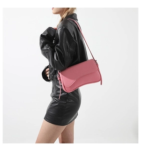 Detailed side view of pink litchi leather shoulder bag worn by model in black outfit