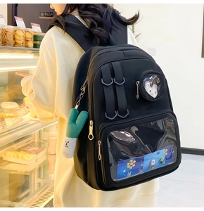 Detail view of black nylon backpack featuring heart-shaped clear window and cute doll