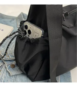 Close-up of black canvas shoulder bag showing side drawstring pocket with phone storage