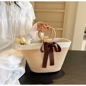Detail showing the woven ring handles and decorative ribbon on the summer tote bag