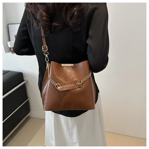 Détail du sac seau en similicuir marron avec chaîne dorée et inscription Fashion