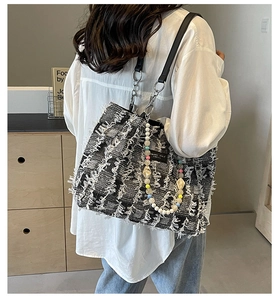 Detailansicht der schwarz-weißen Tweed-Tasche mit bunten Perlen und Metallkettenriemen