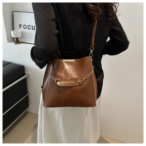 Vue détaillée du sac seau en cuir PU marron avec étiquette fashion et chaîne dorée