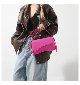 Close-up of bright pink PU leather shoulder bag styled with a dark leather coat