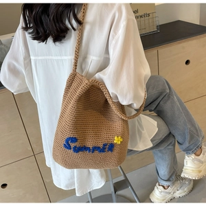 Détail d'un sac bandoulière tissé avec broderie Summer bleue et petite fleur décorative