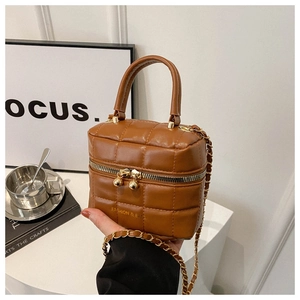 Sac à main carré matelassé caramel avec bandoulière chaîne dorée sur surface blanche