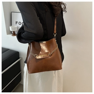 Détail du sac seau en cuir marron foncé avec chaîne dorée et logo de mode élégant
