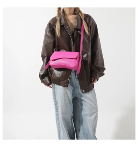 Detail of vibrant hot pink PU leather crossbody bag with lychee texture on model