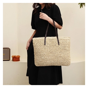 Detail of hand-woven straw tote with premium brown leather straps and sturdy stitching