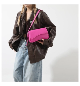 Detail view of pink lychee leather handbag with unique wave curve flap and thin strap