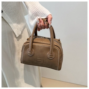 Detail of vintage brown textured leather handbag with white stitching and lady bags logo