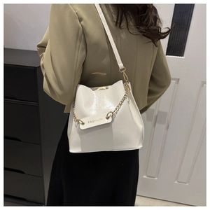 Détail d'un sac seau en cuir PU blanc avec chaîne dorée et étiquette de mode gravée