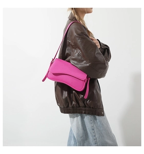Detail of a bright fuchsia PU leather underarm bag with wave cut flap and grain texture