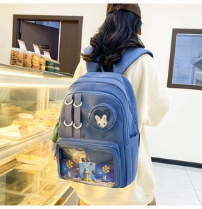 Detail view of blue nylon backpack with transparent window and rabbit plush charm