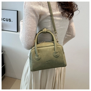 Detail view of light green Boston bag featuring decorative white stitching and adjustable strap