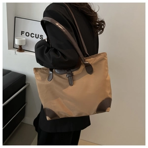 Détail du sac fourre-tout en nylon kaki avec anses en simili cuir marron et base renforcée