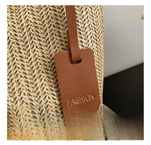 Detail of woven straw texture and premium brown lychee leather tag with gold lettering