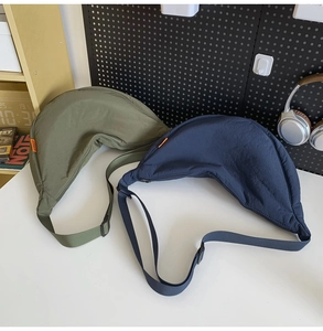 Detail view of nylon crescent bags in olive green and dark blue with adjustable straps