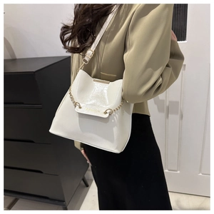 Détail du sac seau blanc cassé avec chaîne dorée et gravure de texte de mode