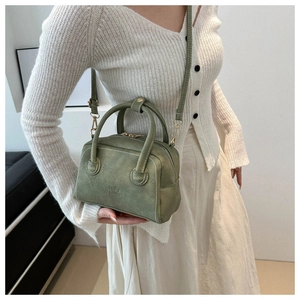 Detail of vintage dark green Boston bag in matte PU leather with embossed logo