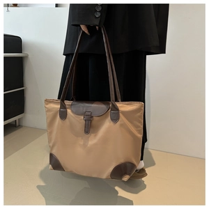 Détail d'un grand sac cabas en nylon kaki avec poignées en cuir marron et boucle en cuir