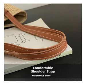 Detail view of woven straw bag with premium brown leather strap and contrast stitching