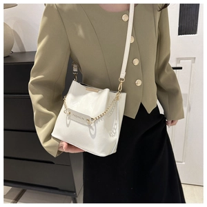 Détail du sac seau en cuir blanc avec chaîne dorée et étiquette logo FASHION