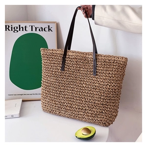 Fashionable hand-woven straw tote bag with brown leather straps for summer beach or casual use