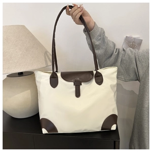 Détail d'un grand sac cabas en toile avec poignées en cuir marron et fermeture à boucle