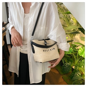 Vue détaillée du sac seau en paille avec bandoulière en cuir noir et fermoir métal