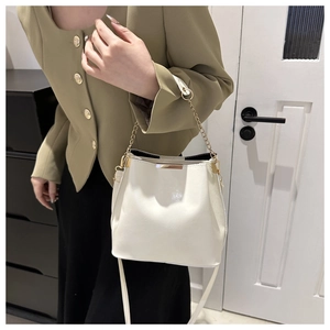 Détail du sac seau crème avec poignée en chaîne dorée et finitions métalliques