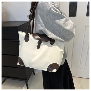 Détail du sac cabas en nylon blanc avec finitions en cuir marron et tissu imperméable