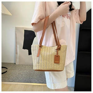 Close-up of beige woven tote bag with herringbone texture and brown leather straps