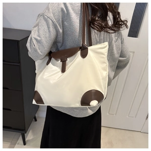 Vue détaillée de l'arrière d'un sac cabas minimaliste crème avec des détails marron
