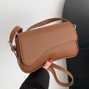 Brown litchi grain leather shoulder bag featuring an asymmetrical wavy flap design