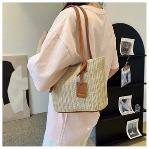 Detail of hand-woven straw tote with brown leather handles and decorative fashion tag