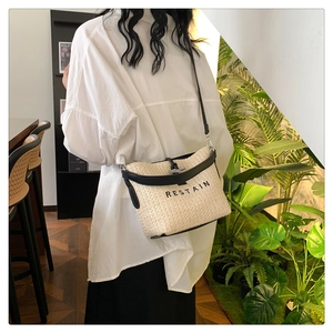 Détail du sac bandoulière tissé avec garniture en cuir noir et logo RESTAIN