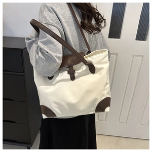 Détail du sac cabas minimaliste en nylon blanc cassé avec des sangles en cuir marron